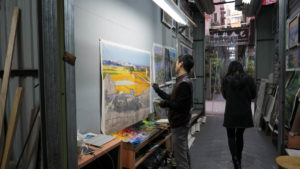 An artist paints in an alley