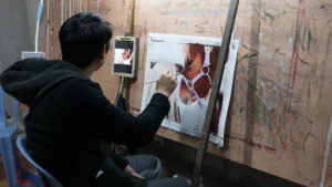 The bar in front of the painting is used to rest the hand for long painting sessions