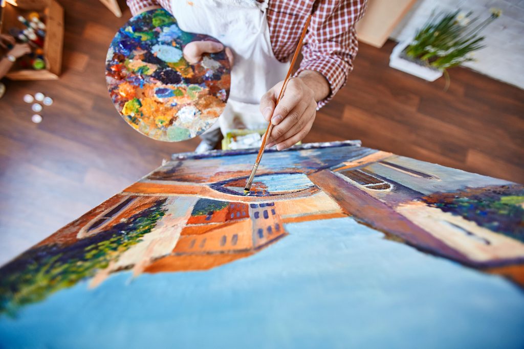 downward view of man painting street of Venice on canvas