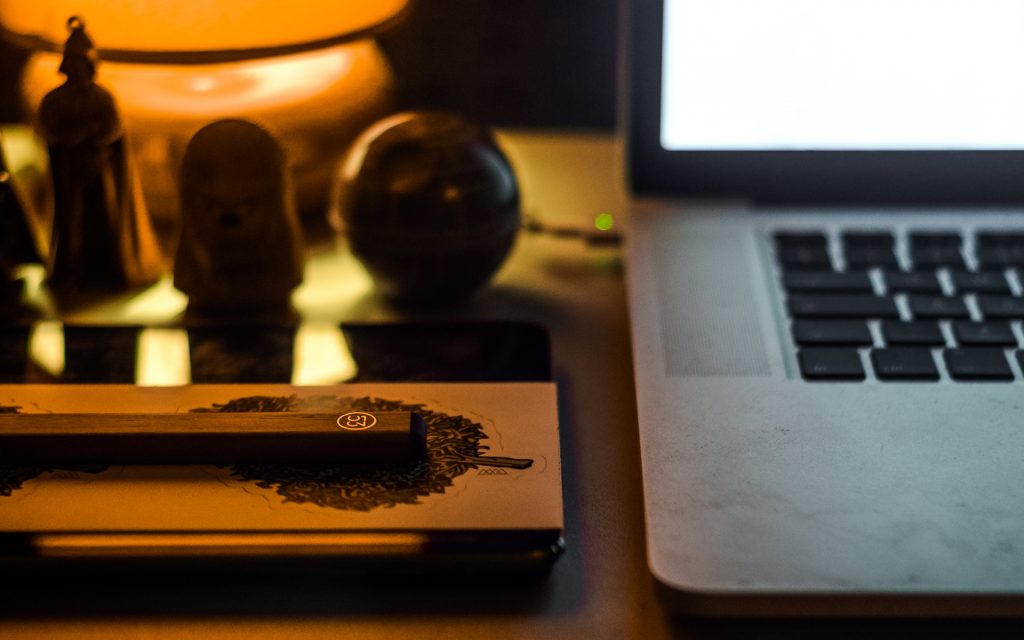 close-up of macbook corner on a desk with lamp on